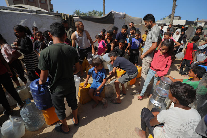Palestinians wait in queue with water jugs to collect water from tankers in Deir al-Balah