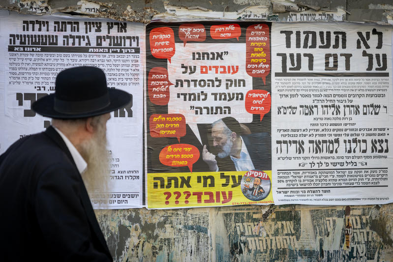 A poster showing Shas leader saying " We are working on a law to regulate the status of Torah students", and underneath reading "Who are you fooling", in the ultra orthodox Jewish neighborhood of Meah Shearim. October 28, 2025.