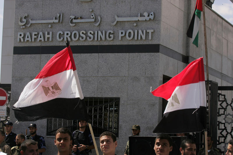 A Palestinian protestor puts up an Egyptian flag during a rally in front of the Rafah border crossing in the southern Gaza Strip on September 16, 2013.